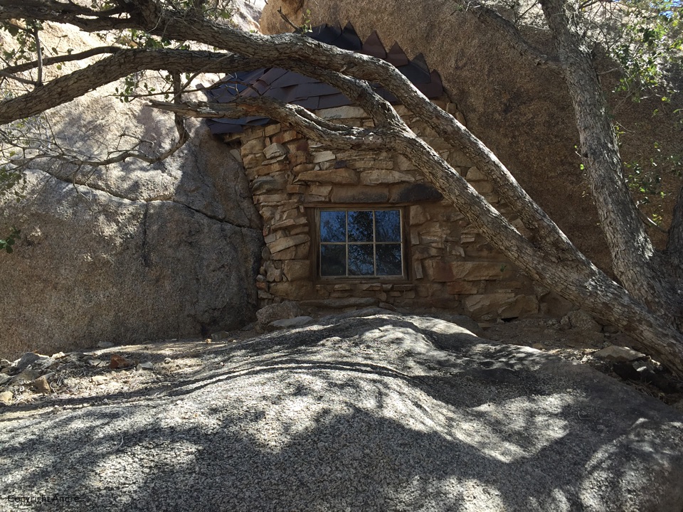 Exterior view of cabin built around some boulders.